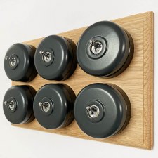 Round Dolly Light Switch 6 Gang Dark Grey on Oak Pattress with Black Mounts