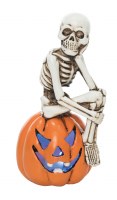 6" LED Skeleton Sitting on a Jack-O-Lantern With the Chin Resting on One Hand