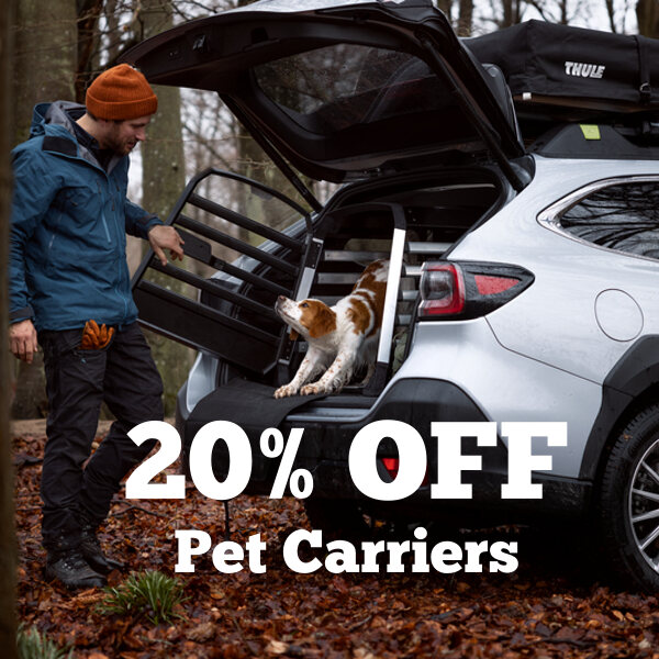 A picture of a man looking at his dog inside of a Thule Allax dog crate inside of a Subaru
