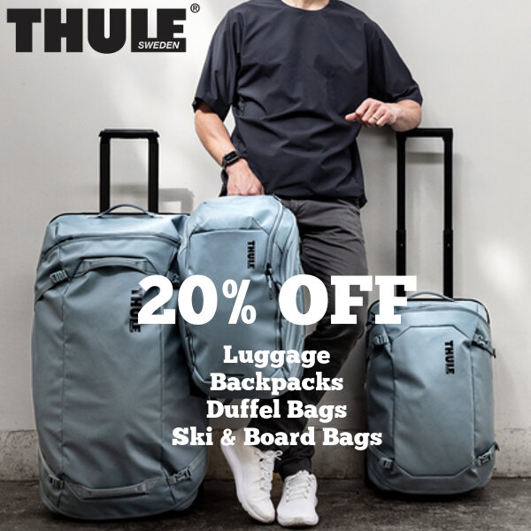 A picture of a man standing with a set of Thule luggage and backpacks