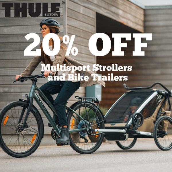 A picture of a mother riding a bike while towing her child in a Thule bike trailer